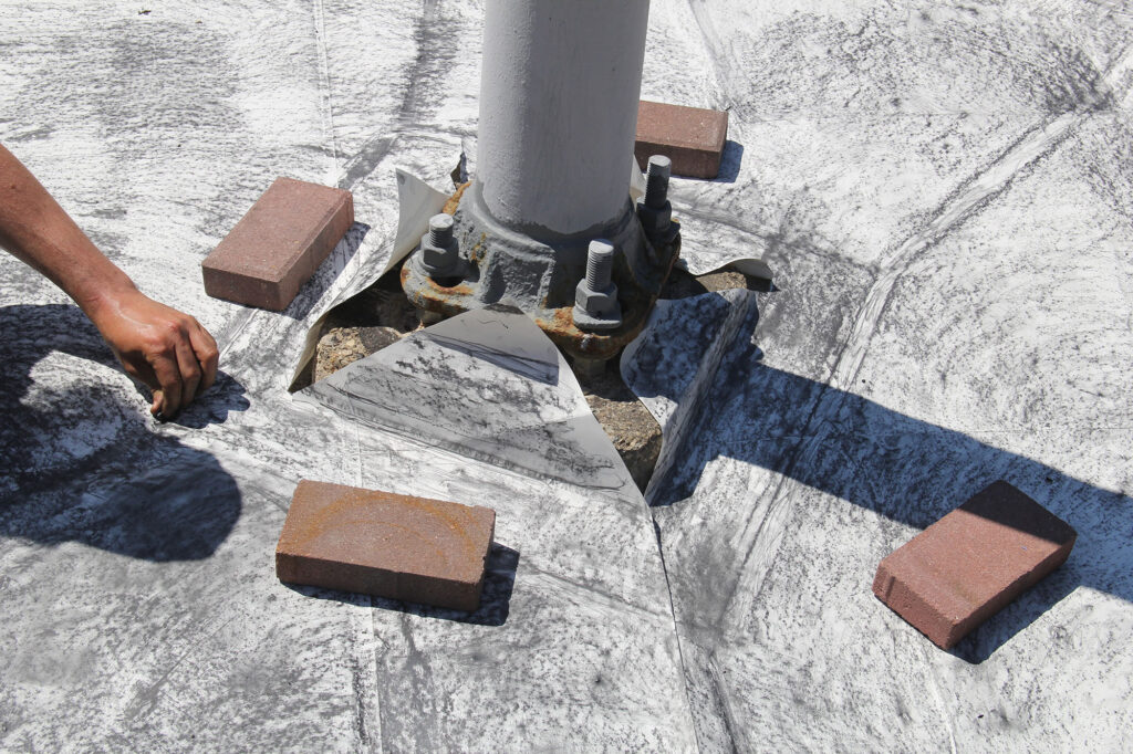 Dylan Cale Jones making a large-scale rubbing of the sidewalk underneath a police surveillance camera